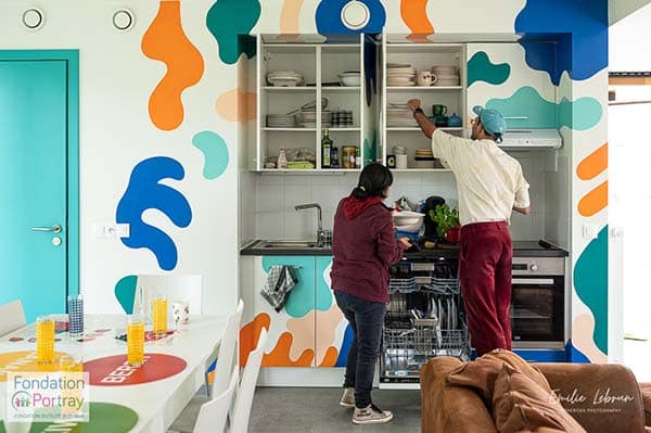 photo de deux personnes dans une cuisine colorée en train de chercher quelque chose dans des placards